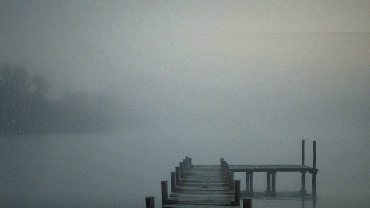 An old wooden dock fading into fog