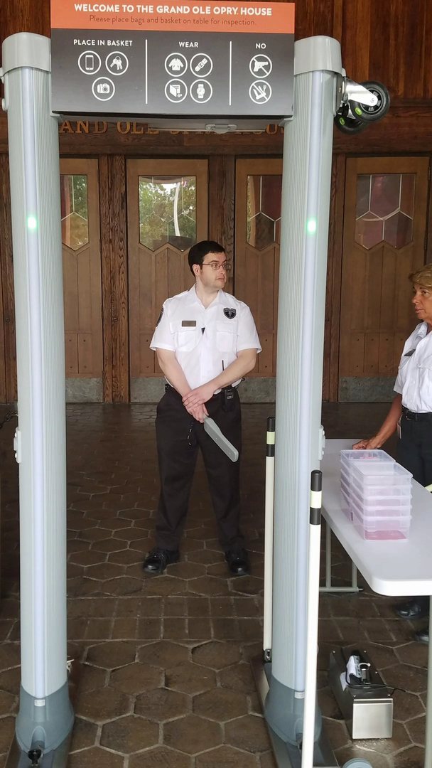 Security guards beside a walk-through metal detector