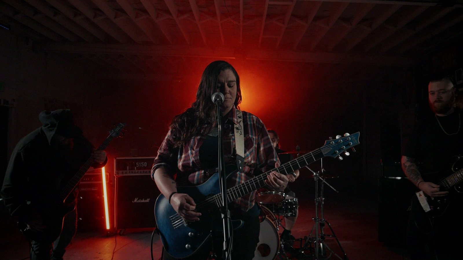 A singer with a guitar under red stage light